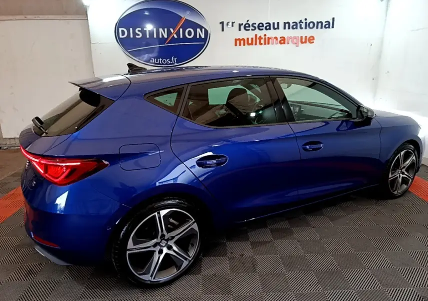 Vue latérale droite d'une SEAT Leon 1.5 eTSI bleu 2021 avec jantes alliage et feux arrière LED allumés.