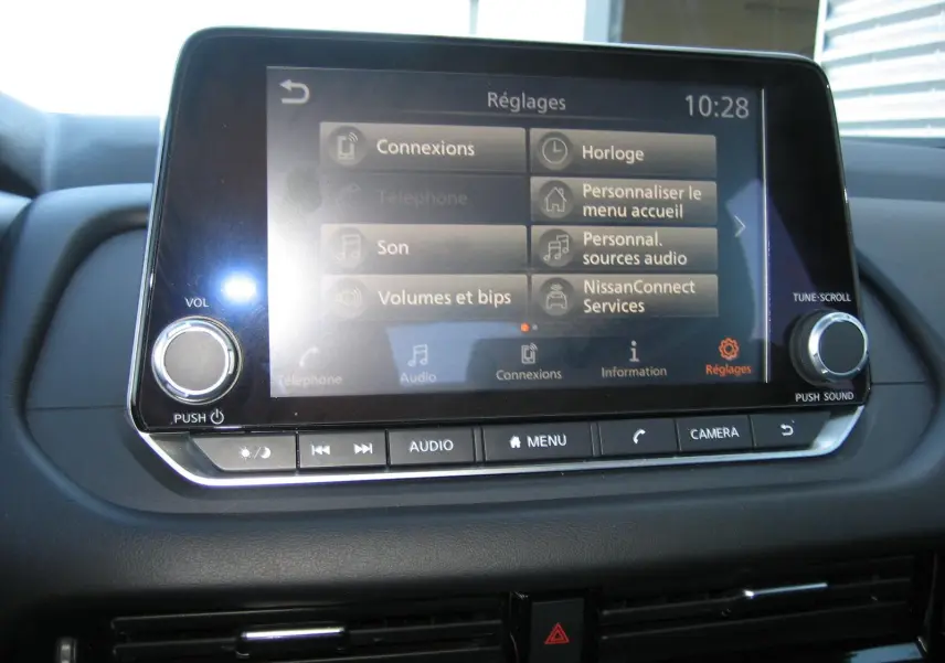 Écran tactile central du Nissan Qashqai 2024 affichant le menu réglages, avec commandes audio et caméra visibles.