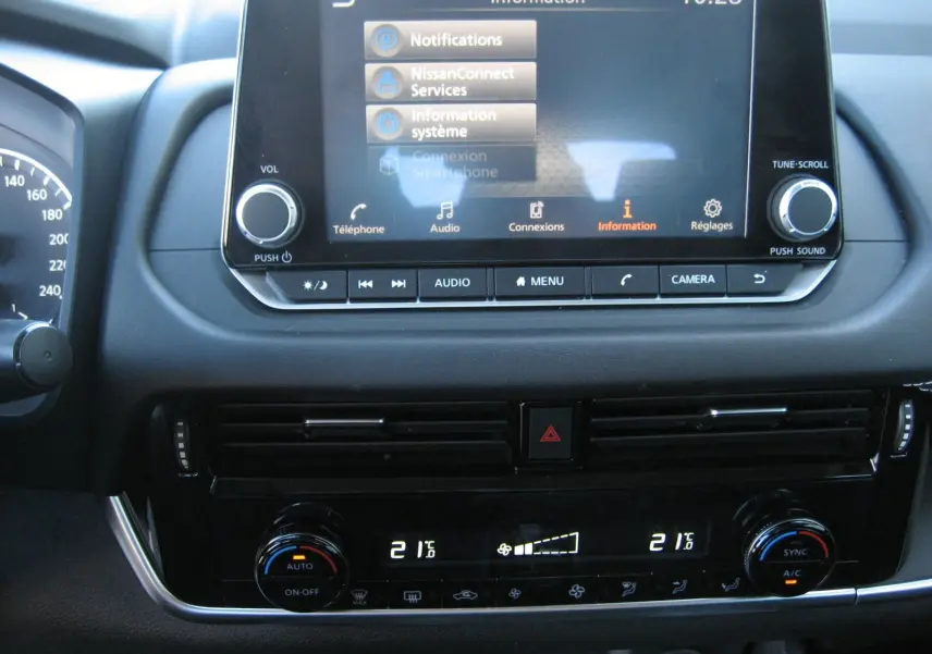 Vue rapprochée de la console centrale du Nissan Qashqai blanc nacré 2024, affichant l’écran tactile et la climatisation digitale.