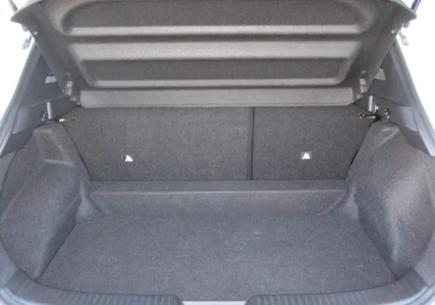 Coffre ouvert d’un Nissan Qashqai blanc nacré 2024, montrant un espace de chargement vide et tapissé de tissu gris.
