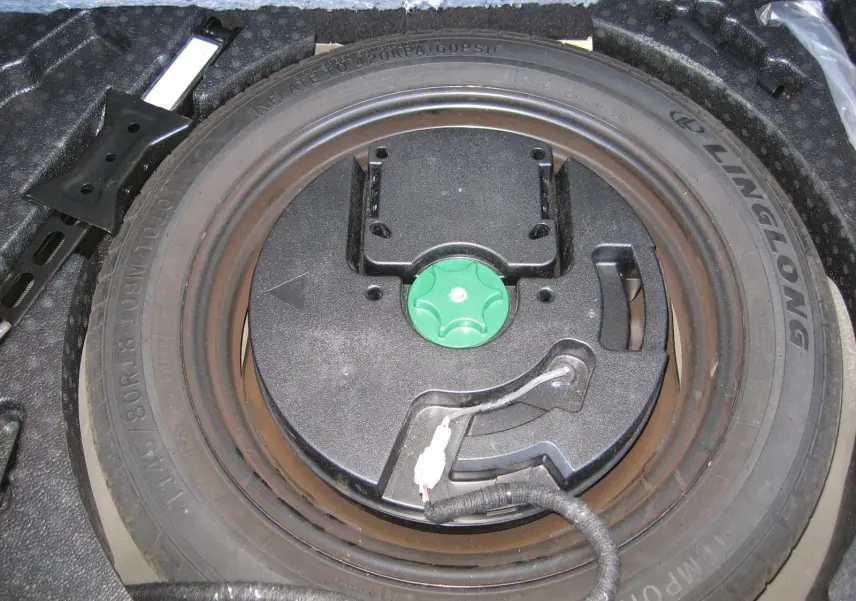 Roue de secours et kit de réparation dans le coffre du Nissan Qashqai blanc nacré 2024, vue plongeante.