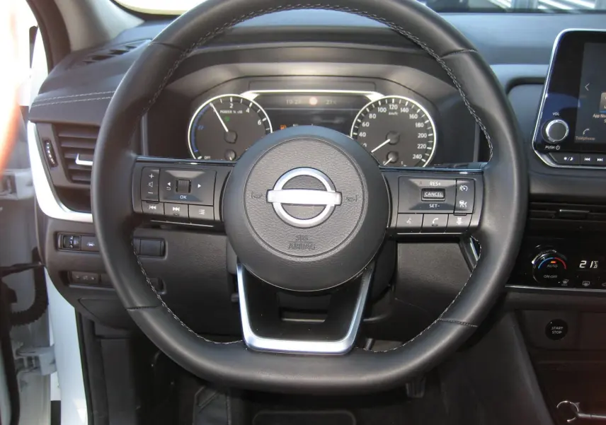 Vue centrée sur le volant noir du Nissan Qashqai blanc nacré 2024, avec tableau de bord et commandes visibles.