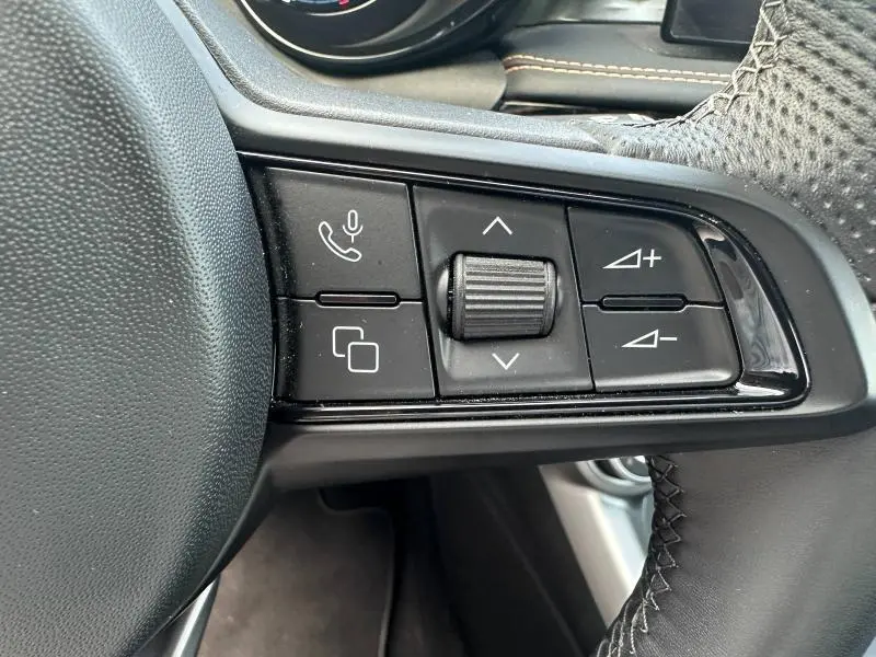Gros plan sur les commandes noires du volant cuir côté gauche de l'Alfa Romeo Tonale gris Vesuvio 2025.