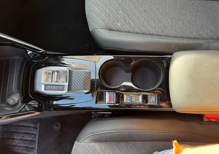 Vue plongeante sur la console centrale noire du Peugeot 2008 Hybrid 136 avec boutons frein à main et mode drive hold.