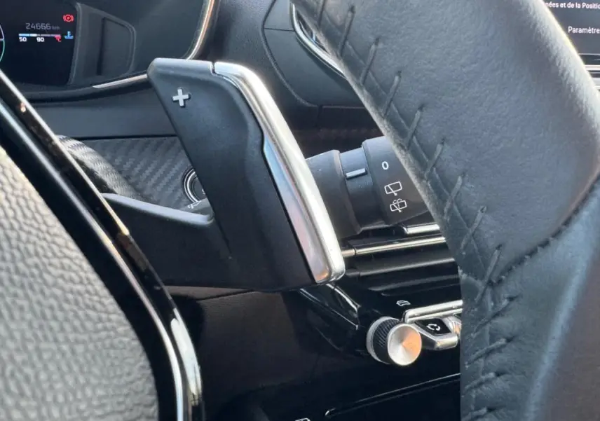 Détail intérieur du Peugeot 2008 Hybrid 136 e-DCS6 Allure 2025, montrant la palette de changement de vitesse côté gauche du volant noir.