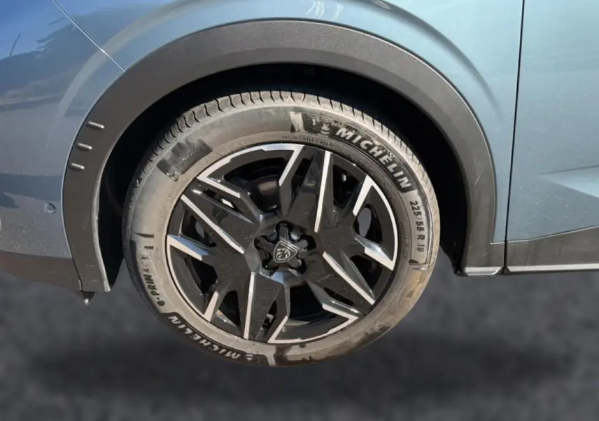 Gros plan sur la roue arrière droite bleu métallisé du Peugeot 3008 1.2 hybrid 145 allure e-dcs6 avec jante alu noire et grise.