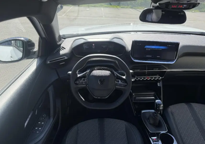 Vue intérieure du poste de conduite du Peugeot 2008 blanc okenite 2024, avec volant compact et boîte manuelle.
