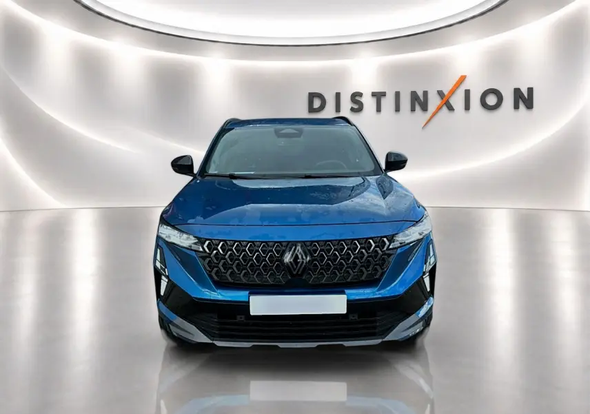 Vue avant d'un Renault Austral bleu outremer avec calandre noire et logo Renault, dans un showroom lumineux.