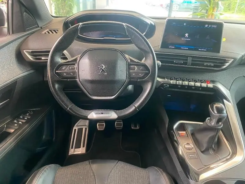 Vue intérieure du poste de conduite du Peugeot 3008 rouge, volant compact et écran tactile central visible.