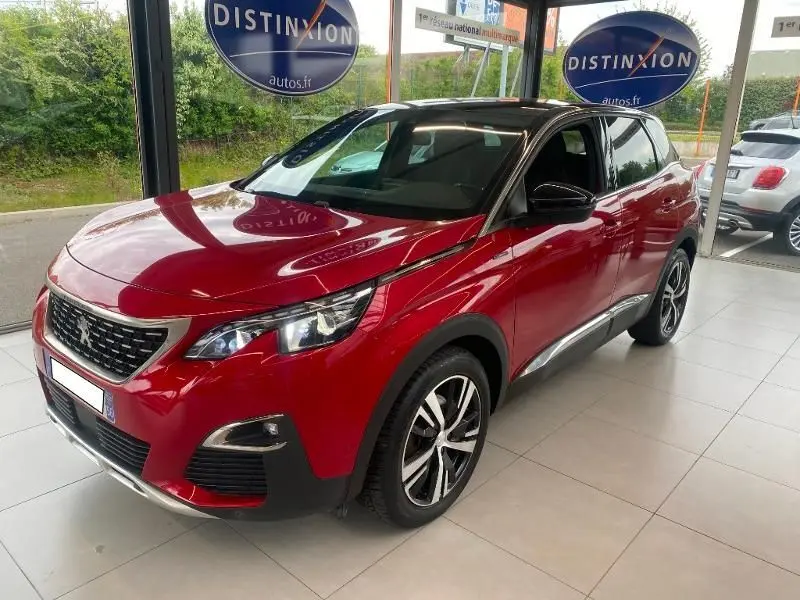 Peugeot 3008 rouge vue 3/4 avant droit en intérieur, avec jantes alliage et toit noir brillant.