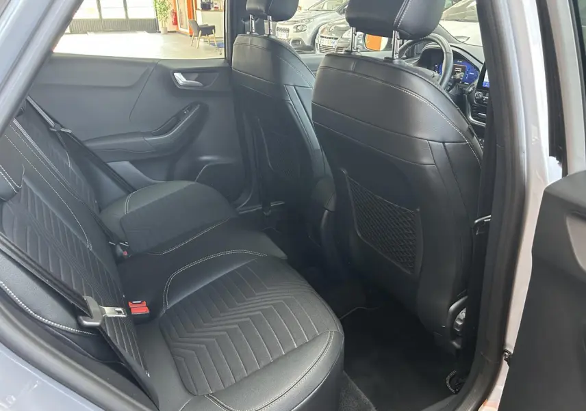 Vue intérieure arrière côté gauche du Ford Puma gris, montrant les sièges arrière en tissu et cuir noir avec surpiqûres blanches.