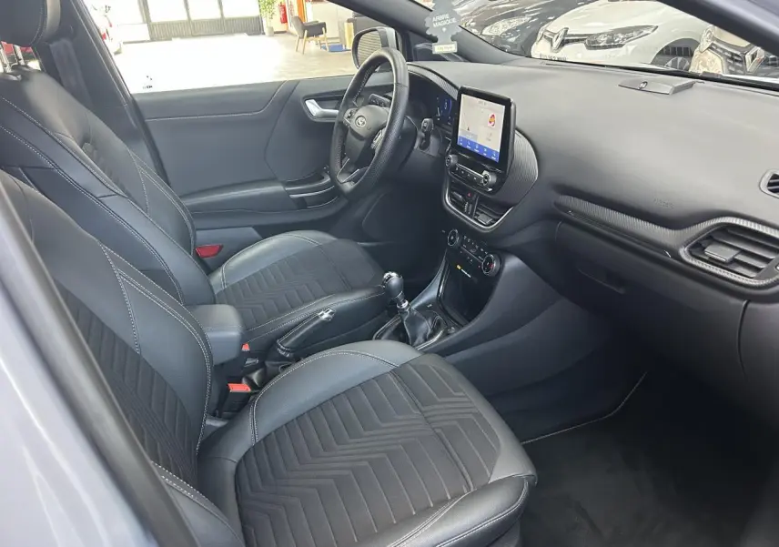 Intérieur avant droit de la Ford Puma 2023 gris, sièges noirs mixte cuir-tissu et tableau de bord avec écran tactile central.