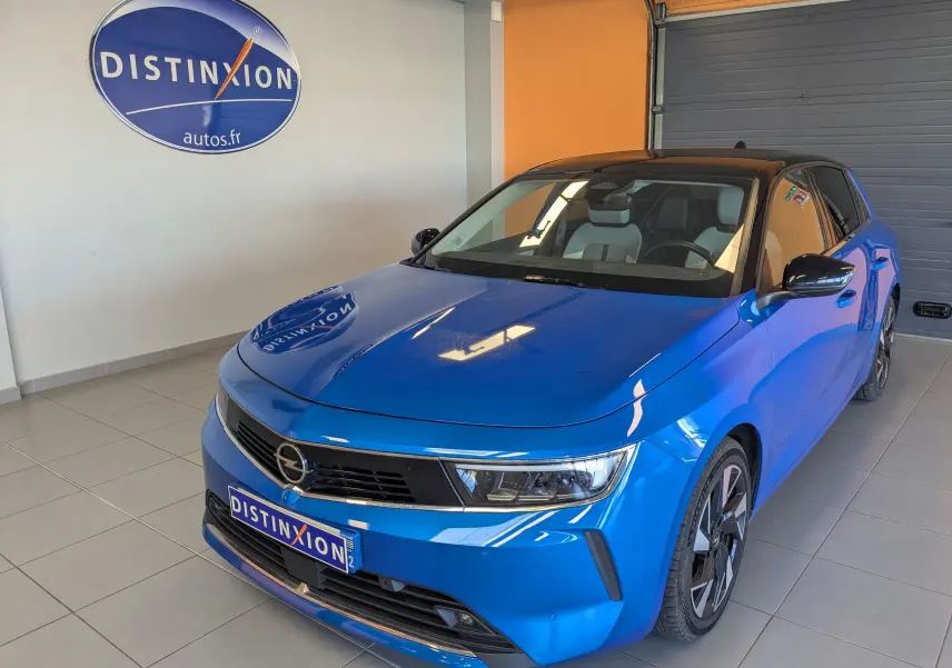 Vue 3/4 avant d'une Opel Astra 2022 bleu avec toit noir et jantes alliage bicolores en showroom.