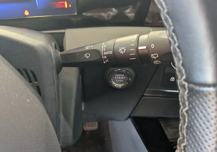 Vue intérieure côté gauche du volant de l'Opel Astra 1.5D 130ch avec bouton start/stop et commandes essuie-glace visibles.