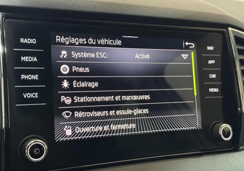 Écran tactile central affichant les réglages du véhicule dans un Skoda Karoq blanc, vue rapprochée intérieure.