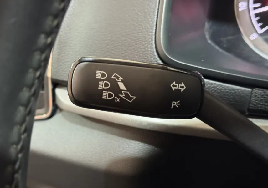 Gros plan sur la manette de clignotants noire à gauche du volant dans l'habitacle du Skoda Karoq blanc 2021.