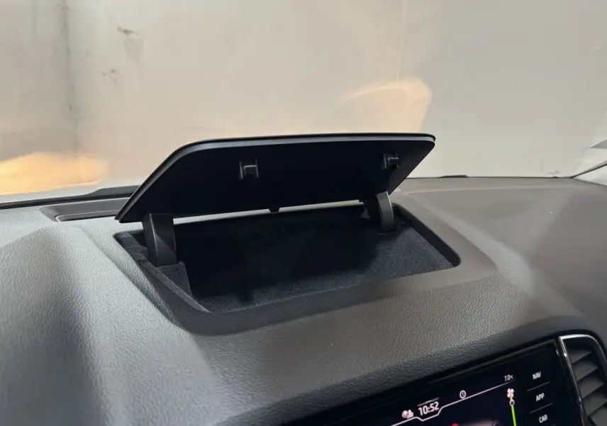 Rangement ouvert sur le tableau de bord noir d'un Skoda Karoq blanc, avec écran tactile visible en bas à droite.