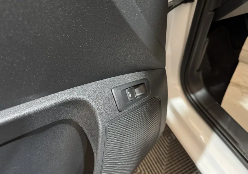 Détail du bouton d'ouverture électrique du coffre sur la porte côté conducteur d'un Skoda Karoq blanc 2021.