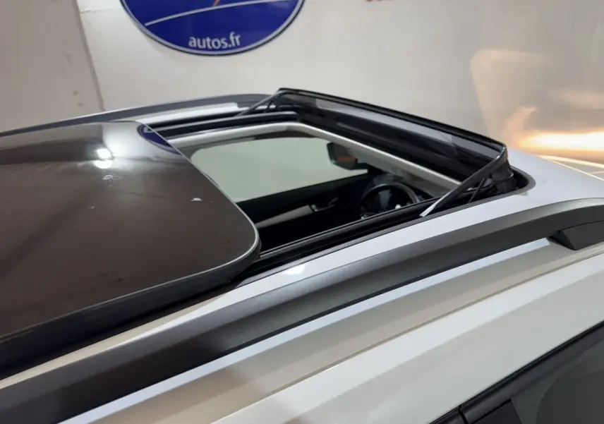 Toit ouvrant panoramique ouvert sur le côté gauche d'un Skoda Karoq blanc, rails de toit gris visibles.