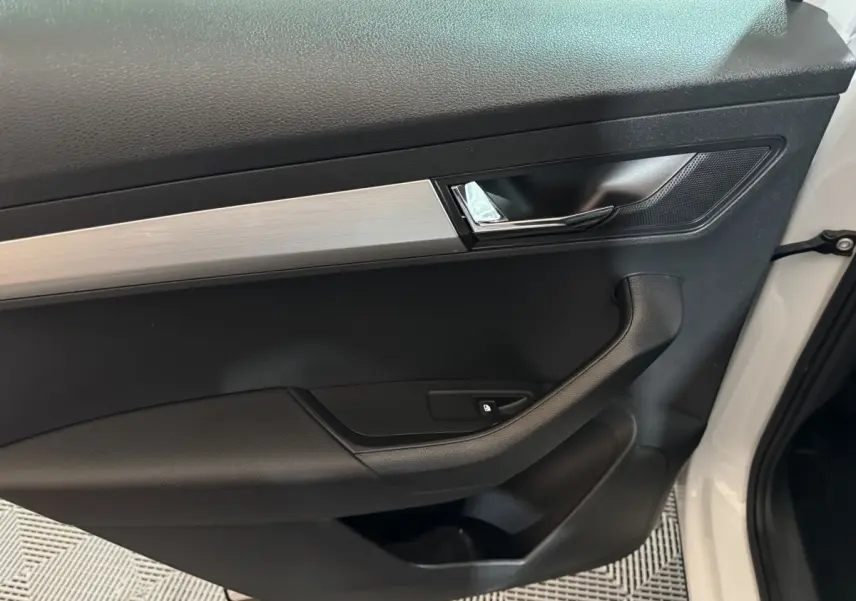 Intérieur côté gauche de la porte avant blanche du Skoda Karoq 2021, avec poignée noire et insert argenté.