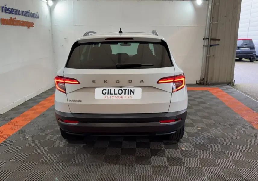 Vue arrière d'un Skoda Karoq blanc 2021 avec feux LED allumés dans un garage éclairé.
