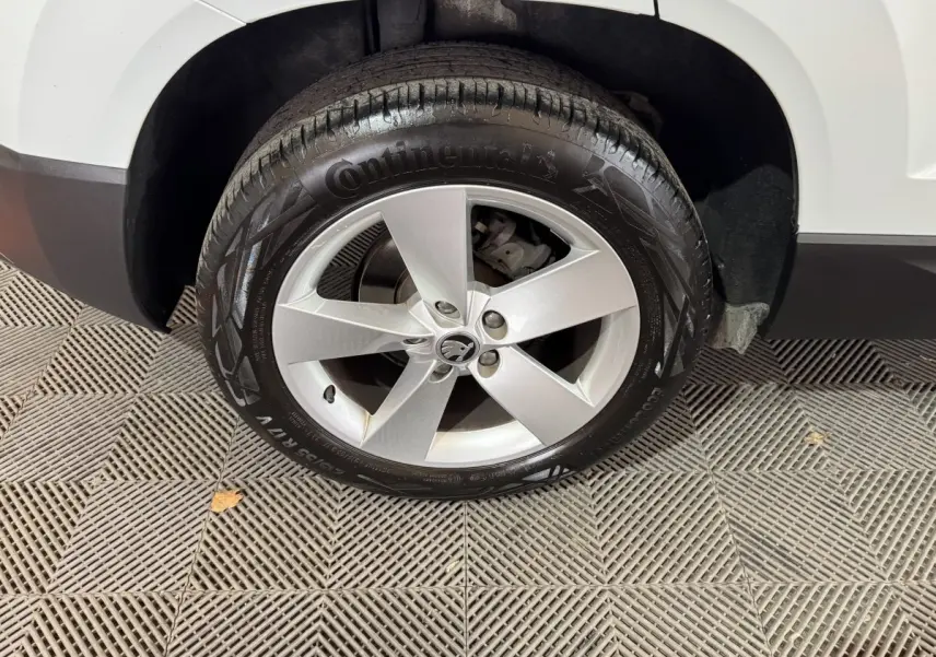 Gros plan sur la roue avant gauche blanche d’un Skoda Karoq 2021 avec jante argentée cinq branches.