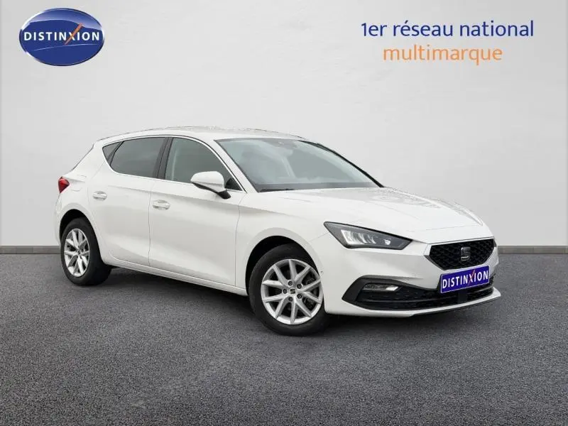Vue 3/4 avant droite d'une SEAT LEON 2.0 TDI 115ch STYLE XL blanche, avec jantes alliage et calandre noire distinctive.