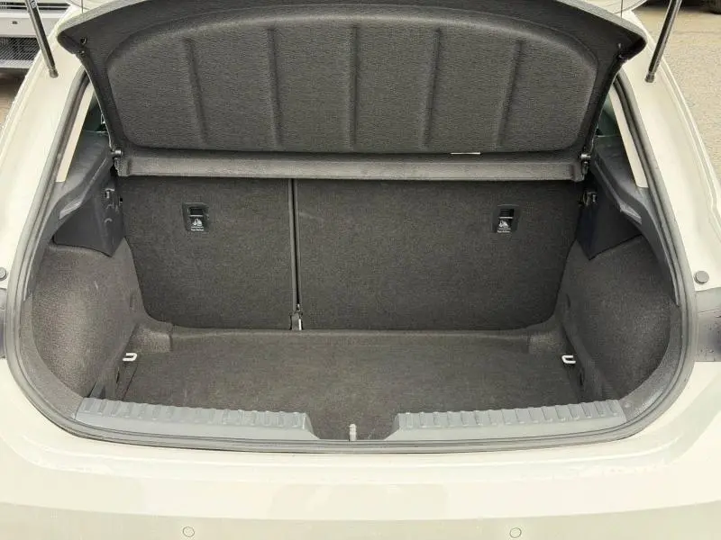 Coffre ouvert vu de l'arrière d'une SEAT LEON 2025 blanche, montrant un espace de rangement vide et doublé de tissu gris.