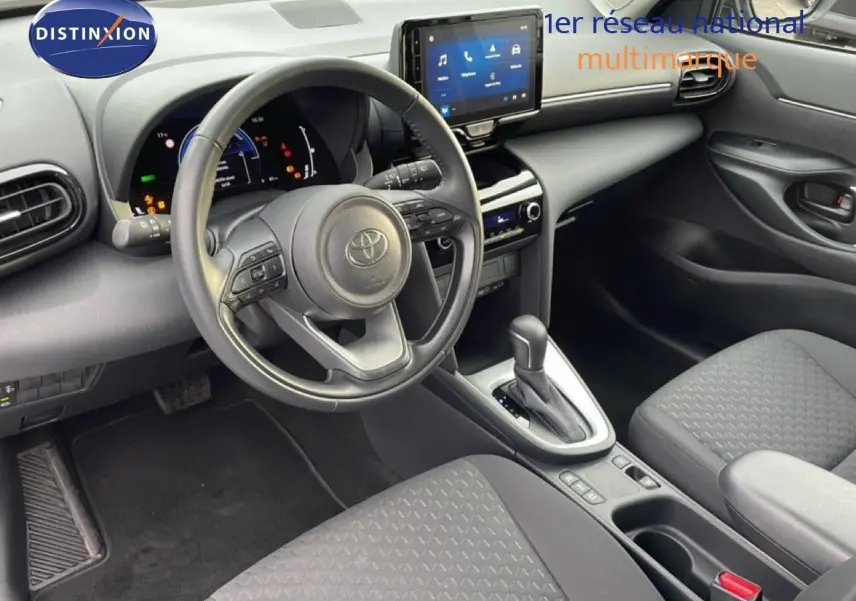 Vue intérieure côté conducteur de la Toyota Yaris Cross 2024, tableau de bord moderne avec écran tactile et volant multifonction noir.