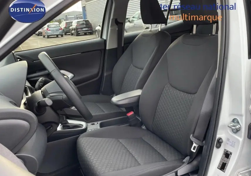 Vue intérieure côté conducteur de la Toyota Yaris Cross blanc pur 2024, montrant les sièges avant en tissu gris foncé.