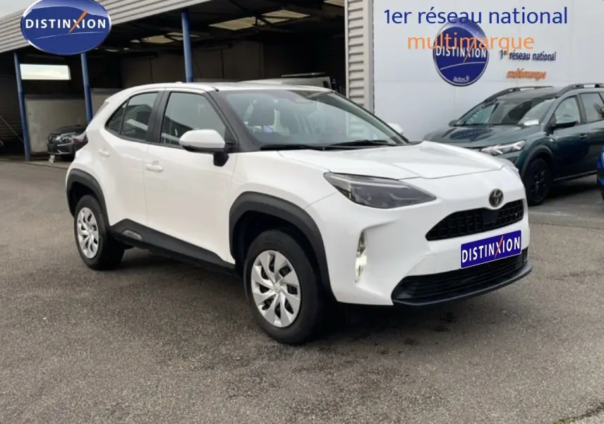 Toyota Yaris Cross blanc pur vue 3/4 avant droit, avec protections noires autour des roues et calandre noire.