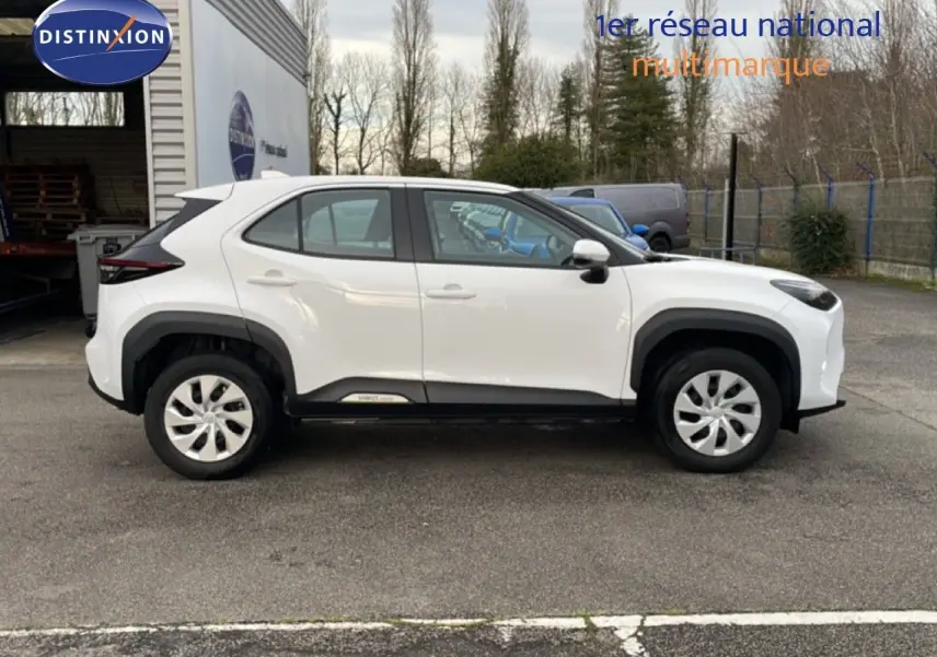 Vue de profil côté gauche d'une Toyota Yaris Cross 2024 blanche, soulignant ses lignes compactes et ses protections noires.