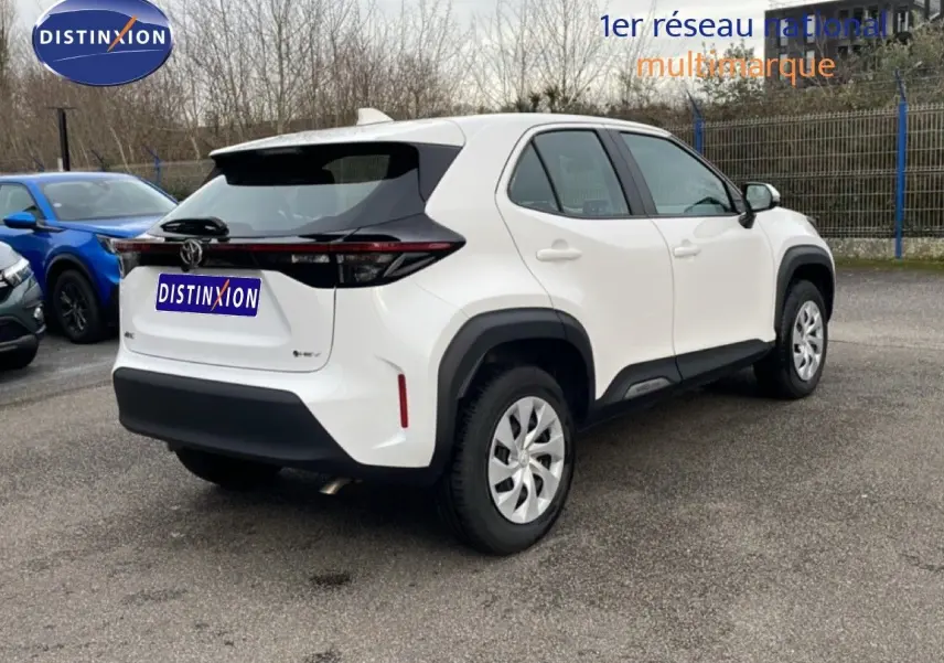 Vue 3/4 arrière droite d'une Toyota Yaris Cross blanche Pure avec détails noirs et feux arrière allongés.