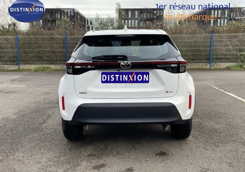 Vue arrière d'une Toyota Yaris Cross 1.5 Hybrid blanc pur, avec feux arrière étirés et pare-chocs noir contrastant.