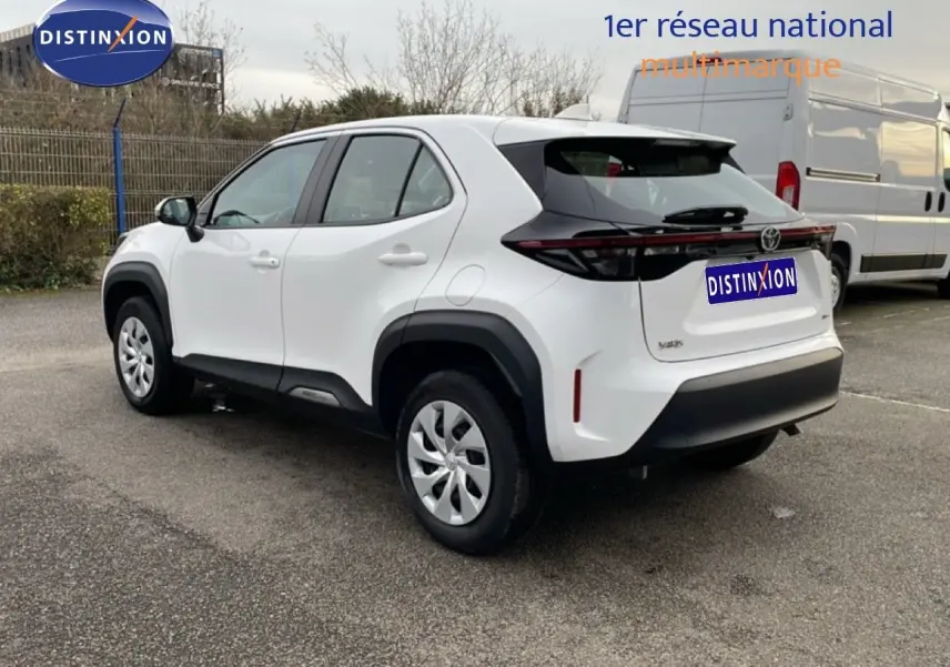 Toyota Yaris Cross blanc pur vue 3/4 arrière droit, avec protections noires contrastantes et jantes acier.