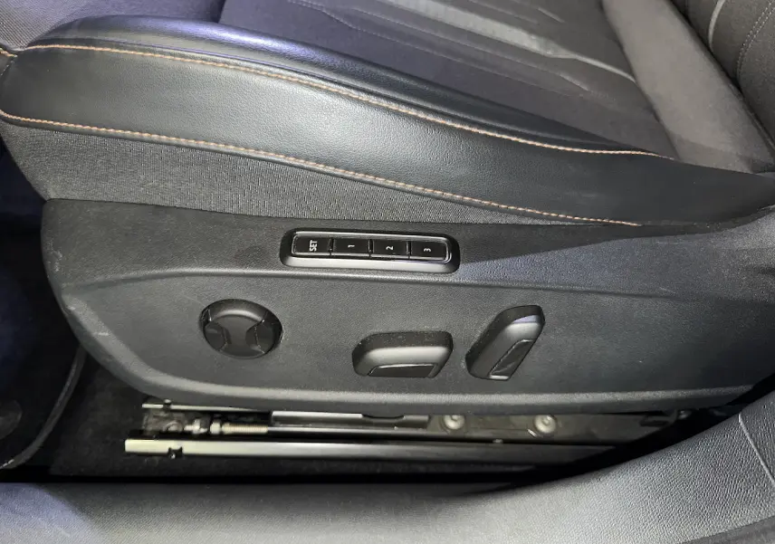 Gros plan sur les commandes électriques du siège conducteur en tissu noir avec surpiqûres cuivrées du CUPRA Formentor gris clair.