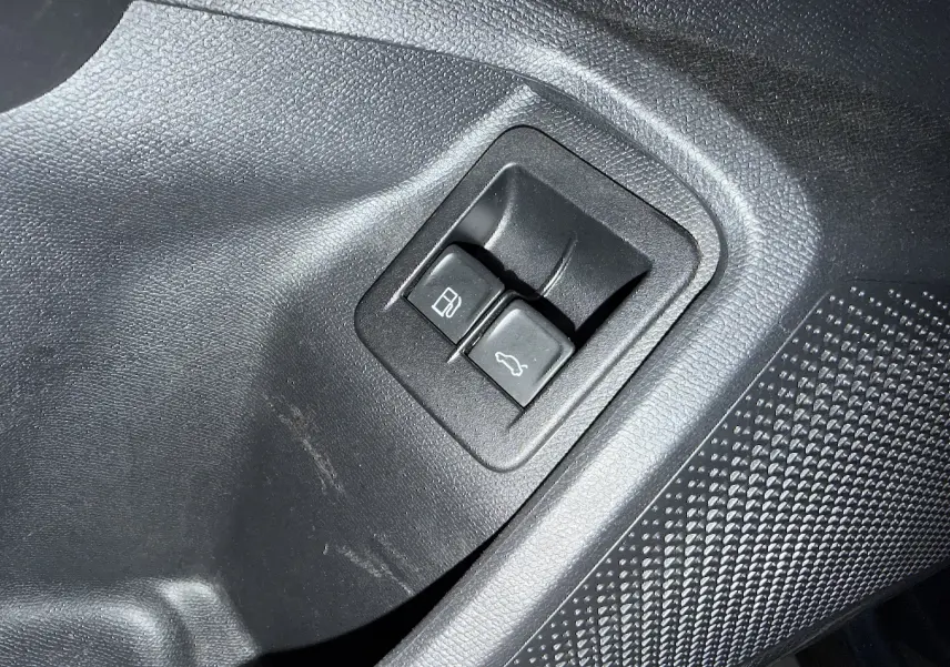 Gros plan sur les boutons d’ouverture de la trappe à carburant et du coffre, intérieur noir d’une CUPRA Formentor gris clair.