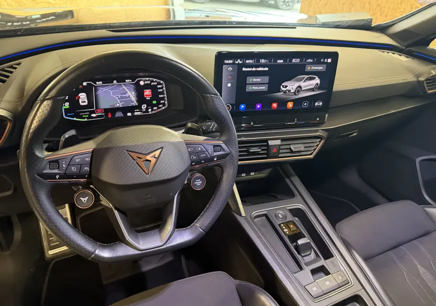 Vue intérieure du tableau de bord et volant super sport noir de la CUPRA Formentor 1.4 Hybrid 245 DSG6 avec écran tactile central allumé.