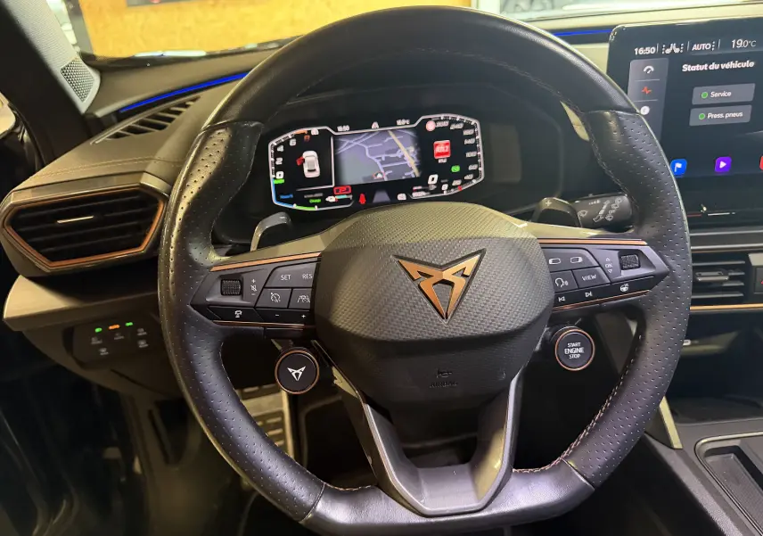 Vue rapprochée du volant super sport noir avec logo cuivré du CUPRA Formentor 1.4 Hybrid 245 DSG6, tableau de bord numérique visible.