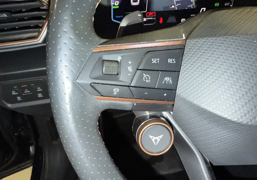 Gros plan sur le volant super sport noir perforé du CUPRA Formentor 1.4 Hybrid 245 avec commandes intégrées et détails cuivrés.