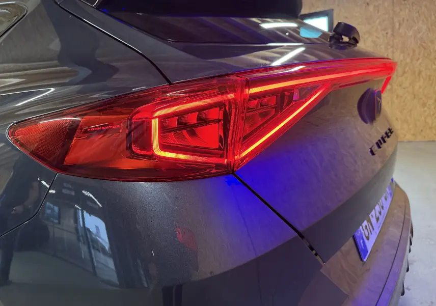 Gros plan sur le feu arrière droit d’un CUPRA Formentor gris clair 2023 avec logo et finition brillante.