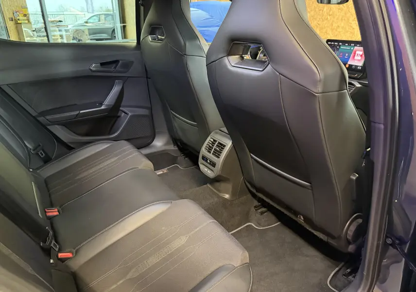 Vue intérieure arrière côté droit du CUPRA Formentor 1.4 Hybrid 245 DSG6, sièges noirs en cuir et tissu avec console centrale ventilée.