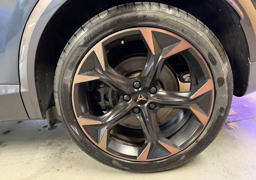 Gros plan sur la roue arrière droite d'une CUPRA Formentor gris clair avec jante cuivre visible.