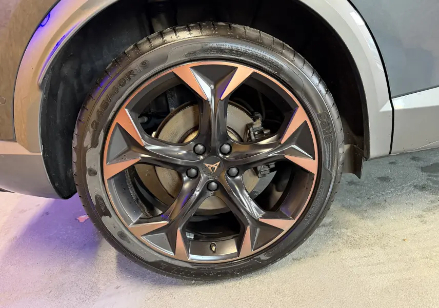 Gros plan sur la roue arrière droite d'un CUPRA Formentor gris clair, mettant en valeur la jante cuivrée et l'arche de roue.