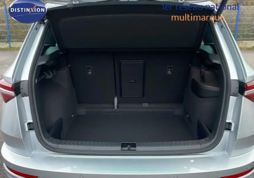 Coffre ouvert vu de l'arrière d'un Skoda Karoq argent 2025, avec intérieur de coffre spacieux et banquette rabattable.