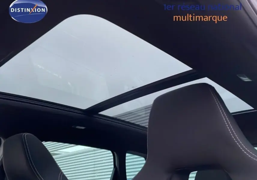 Vue intérieure du toit panoramique et des sièges noirs avec surpiqûres blanches d'un Skoda Karoq argent 2025.