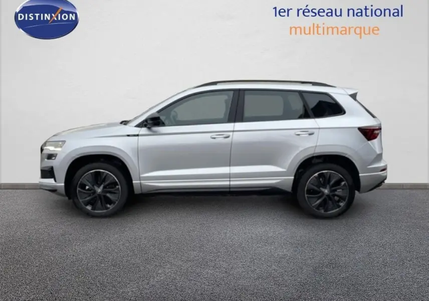 Profil droit d’un Skoda Karoq argent 2025 avec barres de toit et jantes noires sportline.