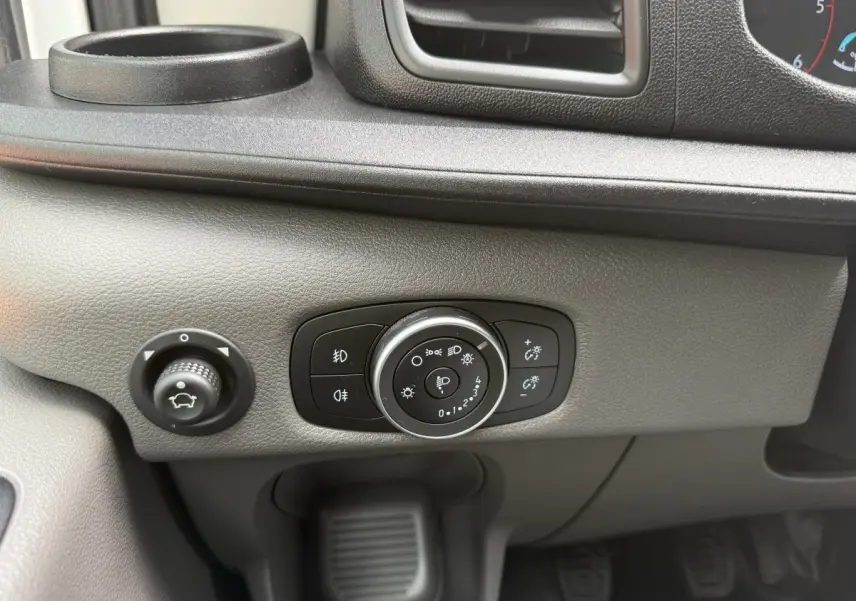 Gros plan sur le panneau de commande des phares et réglage du tableau de bord du Ford Transit Fourgon blanc 2024.