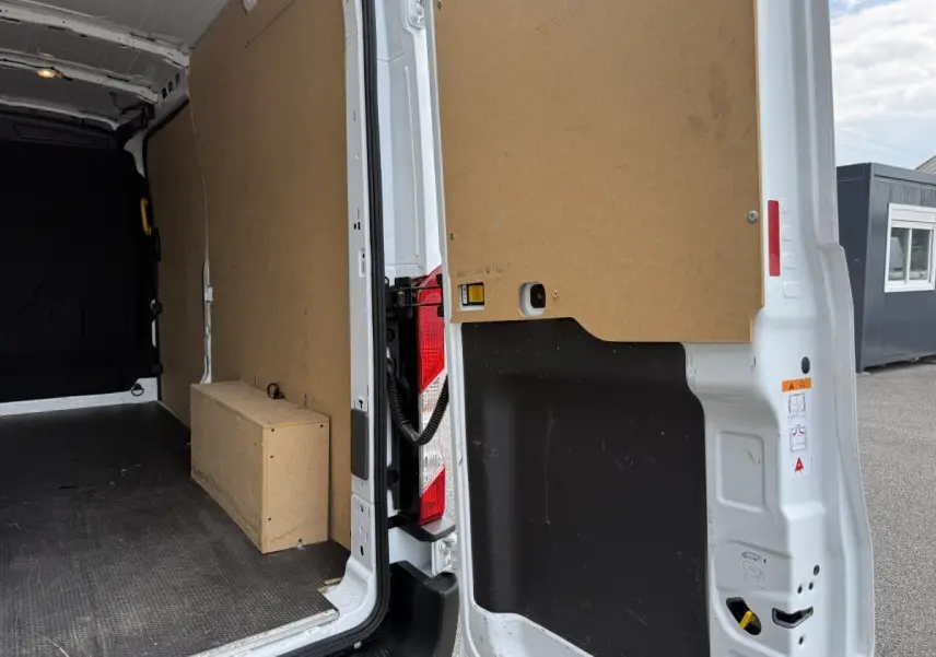 Vue intérieure arrière droite du fourgon blanc Ford Transit 2024, montrant la cloison et l'espace de chargement vide.