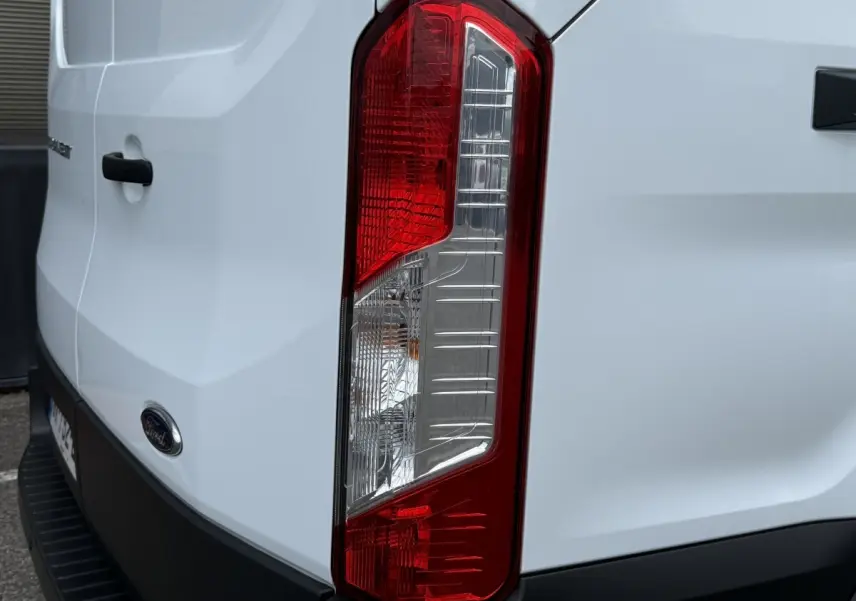 Gros plan sur le feu arrière droit du Ford Transit Fourgon blanc, avec logo Ford visible sur la porte arrière.